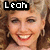 A pixelated image of a smiling woman with curly brown hair, wearing earrings and red lipstick, with text overlays reading "Leah," "Kira," and "PLS MS" in black rectangular boxes.