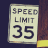 Static pixelated image of a speed limit sign with 'SPEED LIMIT 35' text on a light background, bordered by dark and brownish areas.
