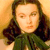Pixelated portrait of a person with long dark hair wearing a green garment against a warm-toned background.