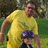 A pixelated static image shows two figures outdoors: an adult in a yellow shirt and sunglasses holding a child wearing a purple cap and dark clothing.