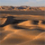 A pixelated landscape with layered brown and orange terrain under a light blue sky, featuring a dark horizontal band across the middle.