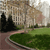 Pixelated static image shows a large building with columns, green lawn, and dark trees under a light sky.