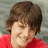 Pixelated image of a person with short brown hair wearing red clothing against a gray background.