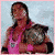 A pixelated image of a person in a pink wrestling singlet holding a championship belt against a light blue background.