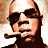 Pixelated static image of a person with dark hair and sunglasses, wearing a dark shirt against a light background.