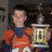 A pixelated image of a person in an orange and blue outfit holding a golden trophy, with pink text reading "I Love Charlie!" appearing on the right side.