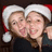 Two people wearing Santa hats pose closely together, one person's arm visible on the right side of the frame.