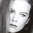 Black-and-white pixelated close-up of a person's face with visible hair on the left side, rendered in grayscale tones at 256x256 resolution.