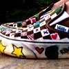 A close-up of a shoe with a patterned upper featuring small icons and symbols, including stars, hearts, and playing card suits, on a light background.