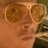 Pixelated text and partial image on black background with repeated phrases, a small photo of a person wearing sunglasses in the top-left corner.