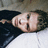 Pixelated close-up of a person's face lying on dark fabric with light background, showing skin tones and facial features.