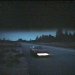 Pixelated static image of a dark landscape with water, distant hills, and a bright horizontal light reflection on the surface.