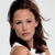 A static pixelated image of a person with long brown hair wearing a white sleeveless top against a light background.