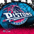 Circular icon with blue and red gradient background featuring stylized text 'DUSTIN' in white, partially obscured by motion blur effects.