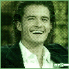 A person in a dark jacket and white shirt smiles broadly across with subtle facial expression changes