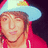Pixelated image of a person wearing a light blue cowboy hat with red trim and yellow emblem, pink jacket, closed eyes, smiling expression.