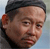 Pixelated static image of a person's face with short dark hair and light skin tone, cropped to show head and upper shoulders against a gradient background.