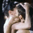 Two figures in intimate embrace with dark hair, one figure's hand near the other's face against a black background.