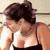 Pixelated static image of a person with dark hair wearing a white tank top and black bottoms, cropped to show upper body against light background.