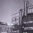 Pixelated grayscale image of a building with vertical and horizontal lines, featuring a tall structure with a flagpole and multiple rectangular sections.