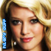 A close-up of a person with blonde hair, wearing a pearl earring, and blue text reading 'HILARY DUFF' vertically on the left side.