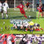 Pixelated soccer scene showing players in red and white jerseys on a green field with goalposts visible.