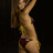 Pixelated static image of a person in a bikini, viewed from the side against a dark background.