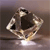 A pixelated, static image of a metallic object with a reflective surface and a dark central cavity, set against a gradient background.