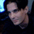 Pixelated close-up of a person's face with light skin tone, dark hair, and closed eyes against a dark background with blue accents.