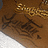 Brown background with golden decorative border, white triangular shape at bottom left, and dark stylized text in center.