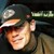 Pixelated static image of a person wearing a dark cap with light brim, smiling face visible in low resolution.