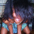 Pixelated image of a character with long dark hair wearing blue shorts, holding an object emitting light.