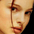 Pixelated close-up of a person's face showing eyes, nose, and mouth with warm skin tones and dark hair strands visible.