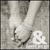 Black-and-white image of two hands holding a small object, with an ampersand symbol and partial text visible in the lower right corner.