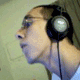A person wearing black over-ear headphones with a light-colored circular center, shown in a sequence of changing head positions against a light green wall.