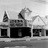 Black-and-white pixelated image of a building with a tower and arched roof, featuring dark rectangular windows and a light background.