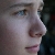 Pixelated close-up of a person's face in profile view showing eye, nose, and mouth with muted skin tones against dark background.