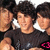 Group of people in black shirts with white collars and pink symbols, some faces partially visible, in a pixelated animation.