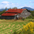 Pixelated static image of a house with red roof and gray walls on a grassy field under blue sky with clouds.