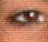 Pixelated image of a stylized eye with multiple colored sections on a checkered background.