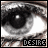 A pixelated grayscale close-up of a human eye with a bright white reflection in the pupil, overlaid with the word 'DESIRE' in blocky pixelated text at the bottom.