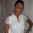 Pixelated image of a person in a white V-neck shirt with one hand on their hip, standing against a muted gray background.