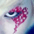 A close-up of a person's eye with red and white patterned makeup extending from the eyelid down the cheek, set against a light background.