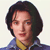 Pixelated portrait of a person with dark shoulder-length hair, wearing a blue jacket over a yellow shirt against a light background.