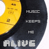 A vinyl record with yellow label and black grooves displays text "MUSIC KEEPS ME ALIVE" in pixelated font, where the word "ALIVE" changes color across frames.