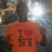 A pixelated image shows a figure wearing an orange shirt with 'I ❤️ MI' text, set against a blurred background of indistinct shapes and colors.