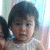 Pixelated image of a person with dark hair tied back, wearing light-colored clothing against a blurred background.