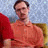 A static image of a person in an orange polo shirt with red and yellow background elements, featuring text overlays.