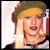 Pixelated image of a person with blonde hair styled in two buns, wearing a green headband and dark clothing with red accents.