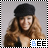 A woman with long wavy brown hair and a black cap smiles while wearing a dark top, with 'BEE' text in blue and black below her.